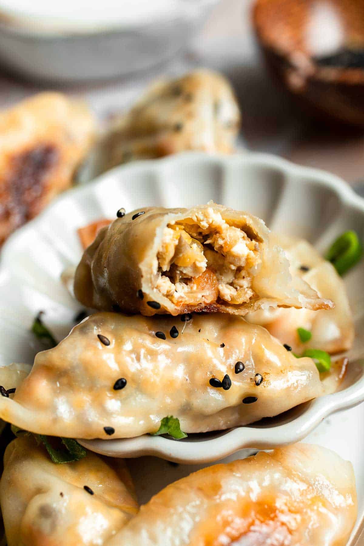 Close-up of a vegetable gyoza bitten open to show the mushroom, tofu, and cabbage filling.