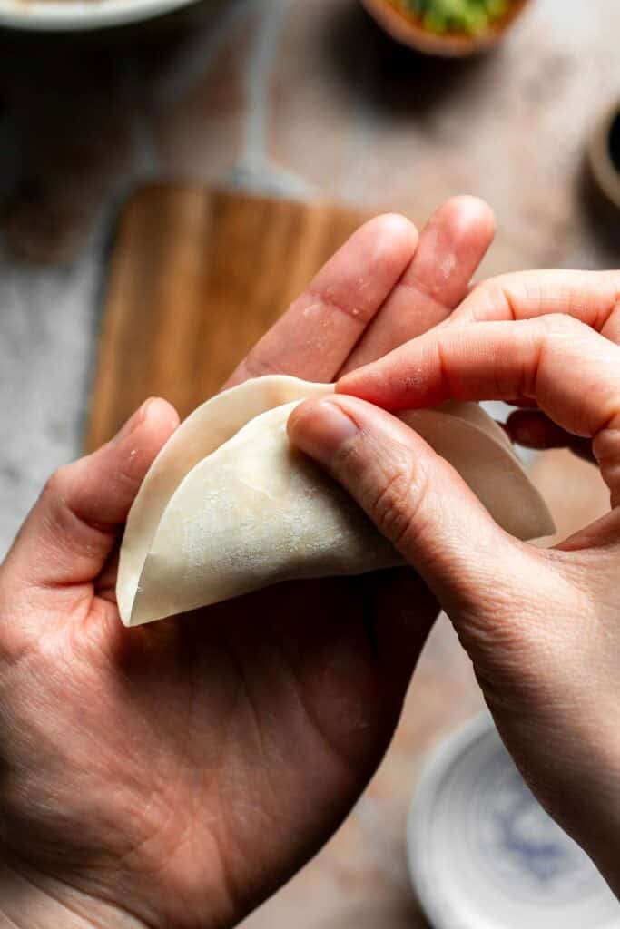 Folding the dumpling wrapper in half over the filling.
