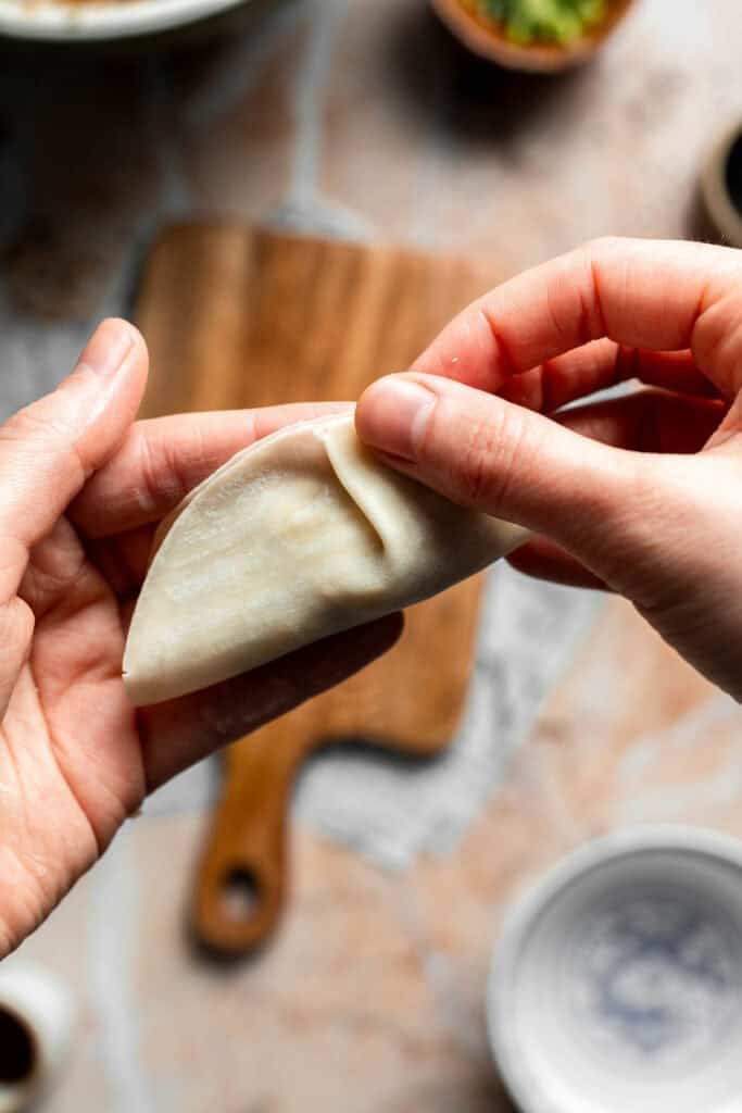 Pleating the edge of the gyoza with the fingers.
