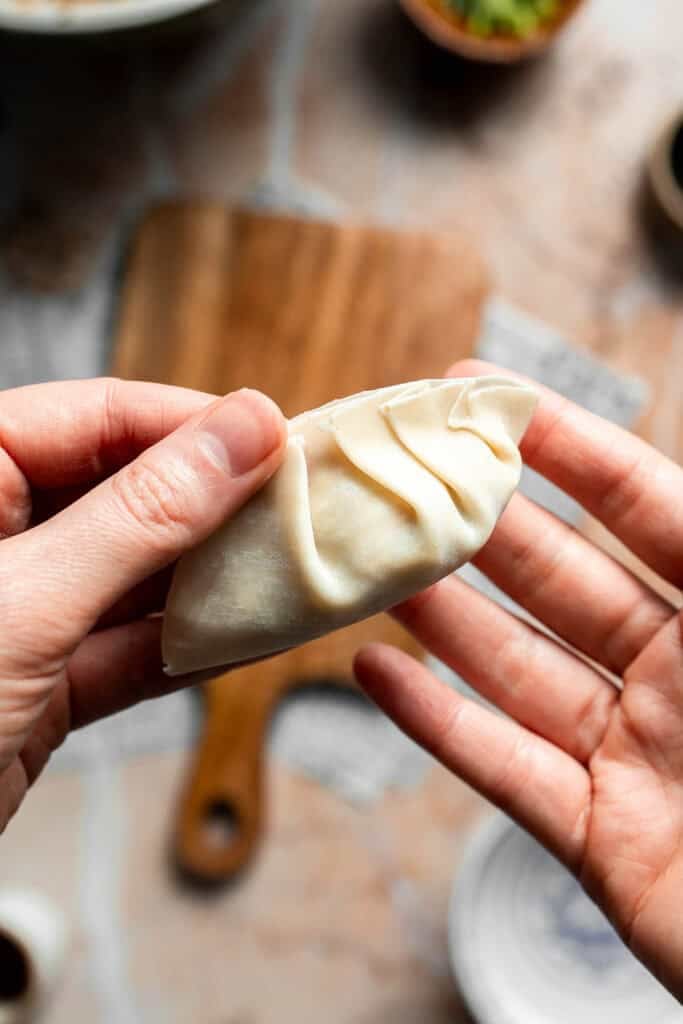 Forming small pleats along the edge of the gyoza.