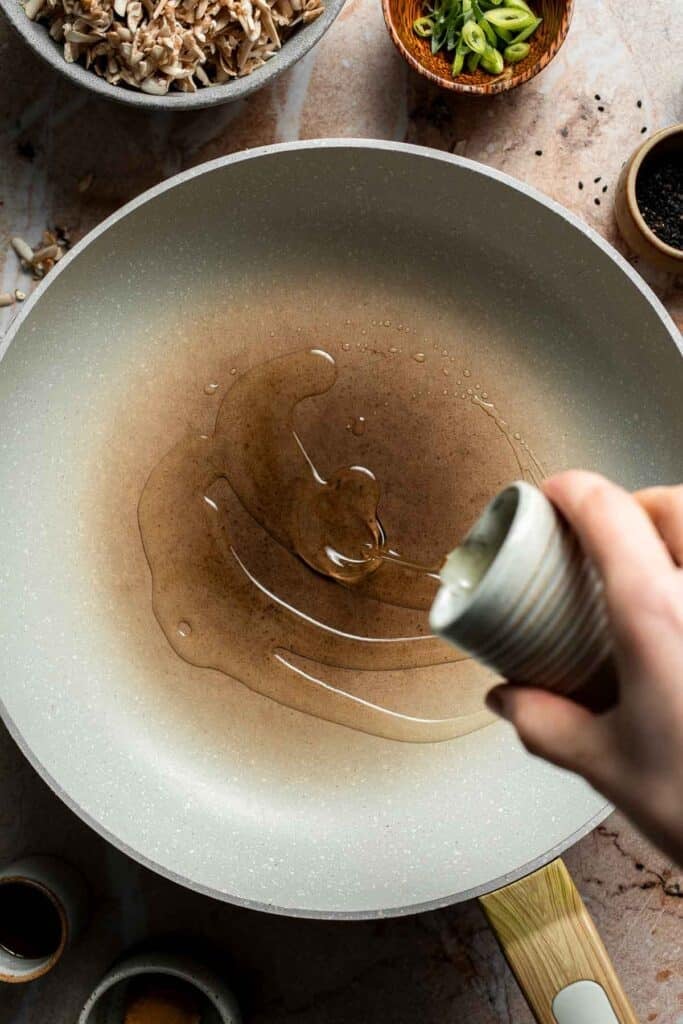 Pouring oil into a skillet.